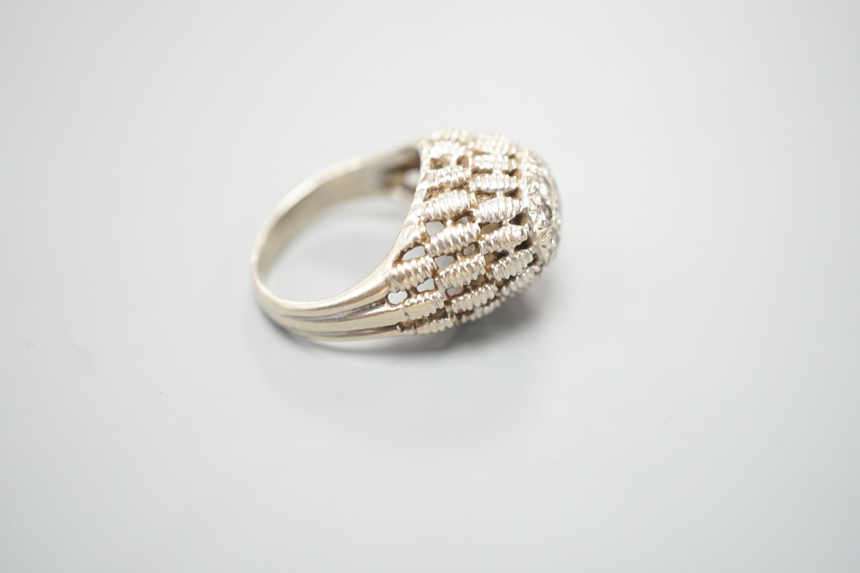 A continental textured white metal and diamond cluster set domed top dress ring, size K/L, gross weight 5.5 grams.